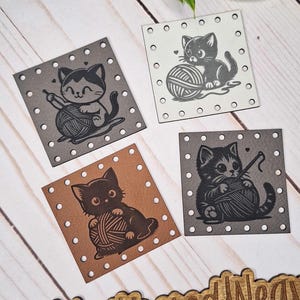 Op de afbeelding: Vier vierkante labels met kattenillustraties. Elk label toont een ander kattenontwerp dat interactie heeft met garen. De labels zijn in tinten grijs, bruin en wit, met kleine gaatjes langs de randen. Er is ook een houten bord met de tekst "@WeatheredWeaves".
