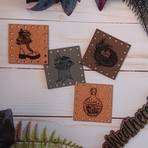 May include: Four cork and leather patches with different designs. The designs include a boot with mushrooms, a mushroom growing from a tree stump, a bird's nest with eggs, and a bottle with mushrooms inside. The patches are all brown and have a distressed look.
