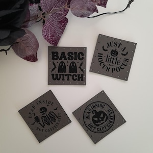 May include: Four gray square patches with black text and images. The patches read "Just a little Hocus Pocus", "Basic Witch", "Dead Inside But Caffeinated" with a skeleton, and "Dead Inside But Caffeinated" with a pumpkin.