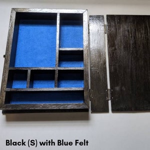 May include: Black wooden box with a blue felt interior and multiple compartments. The box is open and the lid is propped up.