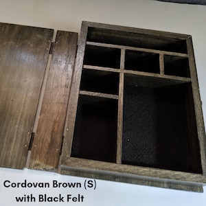 May include: A wooden box with a hinged lid, featuring a compartmentalized interior lined with black felt. The box is labeled "Cordovan Brown (S) with Black Felt".