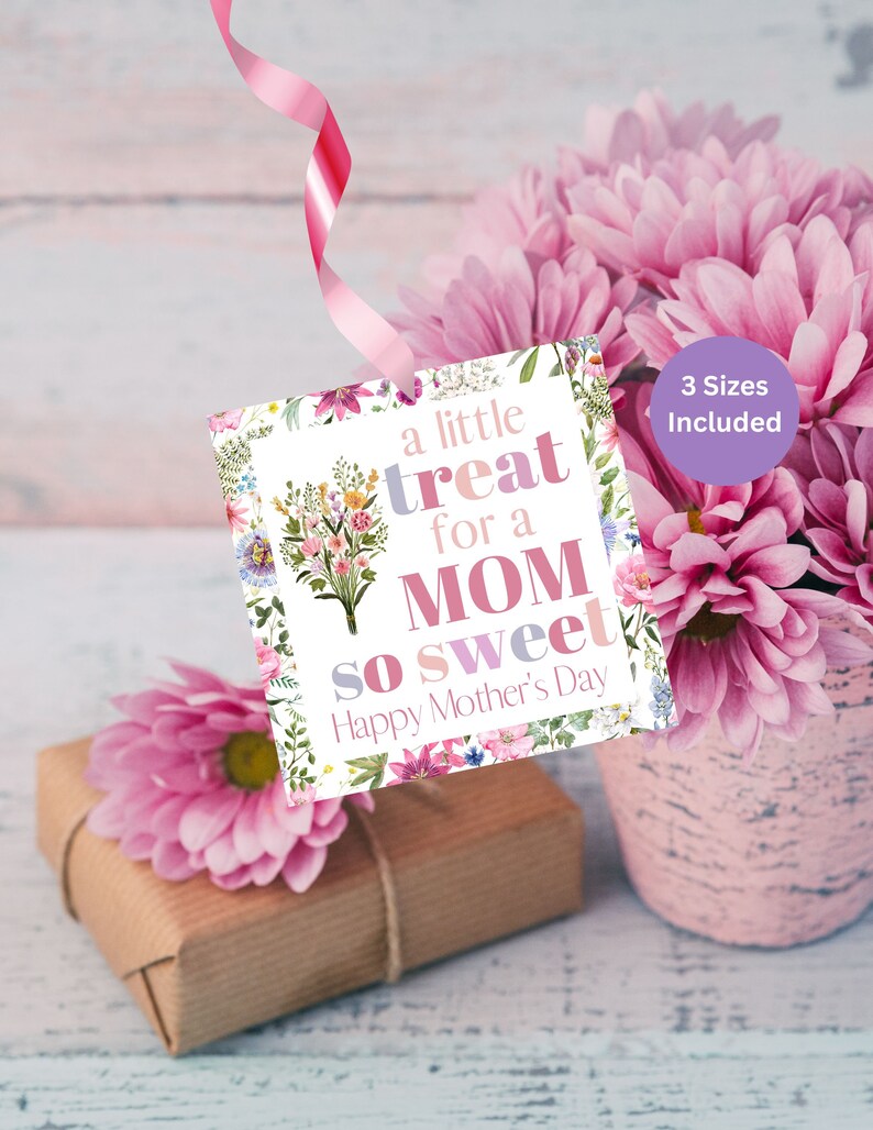 May include: A white gift tag with a floral border and the text "a little treat for a MOM so sweet Happy Mother's Day". The tag is tied with a pink ribbon and is hanging from a bouquet of pink flowers.