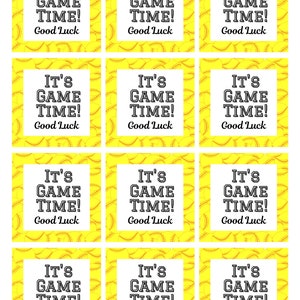 May include: A sheet of softball-themed gift tags. Each tag has a white square with the text "IT'S GAME TIME! Good Luck" in black. The background is yellow with a softball pattern.