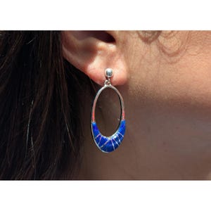 Puede incluir: Pendientes ovalados de plata con una incrustación azul vibrante y un poste de plata. La incrustación azul presenta un diseño geométrico con líneas plateadas. Un accesorio elegante.