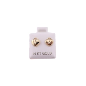 May include: A pair of gold heart-shaped stud earrings with a keyhole design. The earrings are displayed on a white card with the text "14 KT GOLD". The earrings have a polished finish and a classic, romantic style.