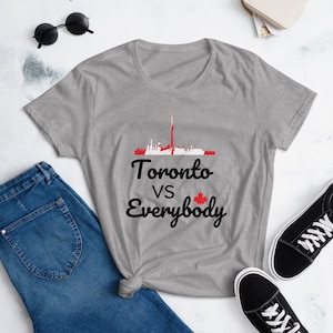 Puede incluir: Camiseta gris con un gráfico negro del horizonte de Toronto y el texto "Toronto vs Everybody" con una bandera canadiense.