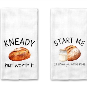 Puede incluir: Dos toallas de cocina blancas con un tema de pan y leche. La primera toalla dice "Kneady but worth it" y presenta un pan. La segunda toalla dice "Start me I'll show you who's boss" y presenta un pan y un frasco de vidrio de leche.
