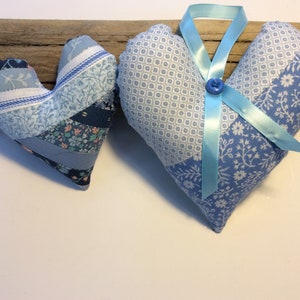 May include: Two blue and white patchwork fabric hearts, one with a blue ribbon tied in a bow.