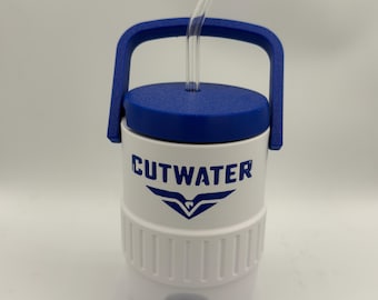 Può includere: Brocca d'acqua isolata bianca e blu con una cannuccia di vetro trasparente. La brocca ha un coperchio e un manico blu e un rubinetto blu. Il testo "CUTWATER" è stampato in blu sul davanti. La brocca è progettata per mantenere le bevande fredde.