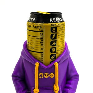 May include: A black and yellow beverage can with the word "REFRESH" and nutrition facts is partially covered by a purple hoodie with yellow drawstrings. The hoodie has the Greek letters ΩΨΦ on the front.