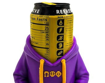 Può includere: Una lattina di bevanda nera e gialla con la parola "REFRESH" e informazioni nutrizionali è parzialmente coperta da una felpa con cappuccio viola con cordini gialli. La felpa ha le lettere greche ΩΨΦ sul davanti.