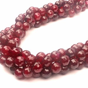 以下が含まれることがあります： 深紅色のファセットカットされた宝石ビーズのストランド。ビーズは丸く、滑らかで磨かれた仕上げになっています。