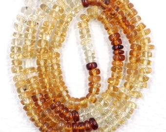 May include: A strand of light yellow, medium yellow, and amber colored gemstone beads. The beads are faceted and have a square shape. The beads are strung on a clear thread.