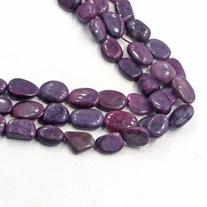 May include: A strand of purple gemstone beads, each bead is oval shaped and has a smooth, polished finish.