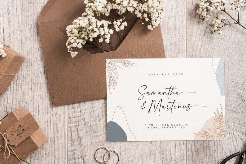 Peut inclure: Une carte blanche avec des formes abstraites brunes et bleues et des illustrations florales dor&eacute;es. Le texte sur la carte indique "Save the Date" suivi de "Samantha & Martinus" et "6 PM in the evening, Lyon, France 1299".
