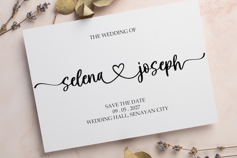 May include: A white save the date card with black text. The text reads "The Wedding of Selena & Joseph" with a heart symbol between the names. The date is 09.05.2027 and the location is "Wedding Hall, Senayan City".