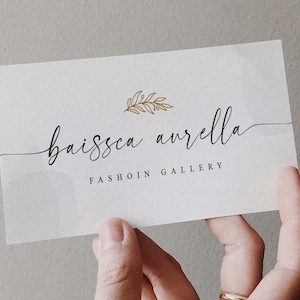 Peut inclure: Une carte de visite blanche avec le texte "baissca aurella FASHION GALLERY" en &eacute;criture cursive noire. Un motif de feuille d'or se trouve au-dessus du texte.