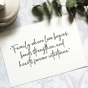 May include: A white card with black calligraphy that reads "Family where love begins, bonds strengthen, and hearts forever intertwine."
