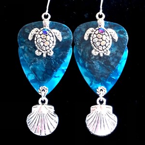 May include: A pair of blue and silver guitar pick earrings with a sea turtle charm and a seashell dangle.