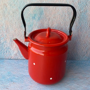 May include: Red enamel teapot with a black handle and white polka dots.