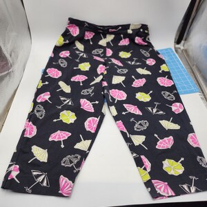 May include: Black pants with a white, pink, and green umbrella print.
