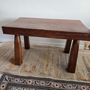 May include: A rustic wooden coffee table with a rectangular top and four legs. The table has a dark brown finish and a slightly distressed look.