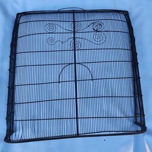 May include: Black metal fireplace screen with a decorative design of swirls. The screen is made of wire mesh and has a curved top.
