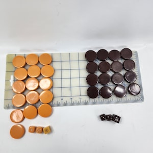 May include: An overhead shot shows a collection of game pieces. There are orange and brown circular game pieces, along with dice. The orange pieces are arranged on a grid, while the brown pieces are grouped together. The dice have white markings.