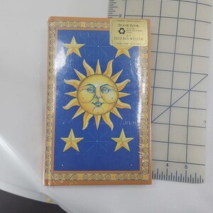 May include: A deck of cards with a blue background, featuring a yellow sun with a face and four yellow stars. The deck is wrapped in clear plastic and has a sticker that says "Blank Book" and "Free Bookmark".