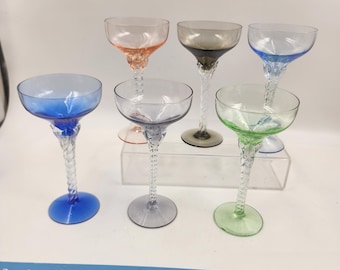 Könnte beinhalten: Satz von sechs Vintage-Stielgläsern mit gedrehten Stielen. Die Gläser sind in verschiedenen Farben, darunter rosa, grau, blau, grün und klar.