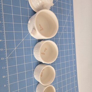 May include: Set of five white ceramic nesting boxes with a hedgehog design. The boxes are decorated with a wood grain pattern and have the numbers 1 to 5 written on them.