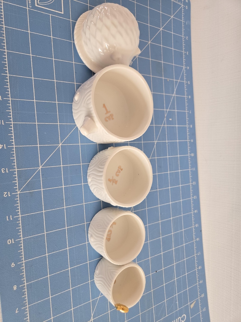 May include: Set of five white ceramic nesting boxes with a hedgehog design. The boxes are decorated with a wood grain pattern and have the numbers 1 to 5 written on them.