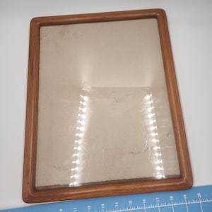 May include: A wooden picture frame with a clear glass front and a light brown mat. The frame is approximately 8 inches by 10 inches.
