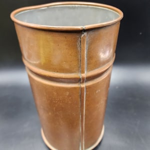 May include: A copper vase with a hammered finish and a slightly rounded shape.