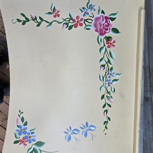 Puede incluir: Bandeja de madera color crema con diseño floral pintado a mano. La bandeja presenta una gran rosa rosa, flores rojas y azules y hojas verdes. Tiene asas.