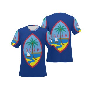 May include: A blue short-sleeved t-shirt featuring the Guam flag design on the front and back. The emblem displays a palm tree, a proa boat on blue water, and yellow sand, with the red-bordered almond shape and the word GUAM printed in red.