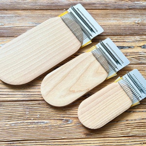 Peut inclure: Trois aiguilles à tricoter en bois avec des dents métalliques. Les aiguilles sont de tailles différentes et sont disposées en rangée sur une surface en bois.