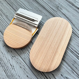 May include: Two wooden knitting looms, one round and one oval, with a metal knitting needle tool on top of the round loom.