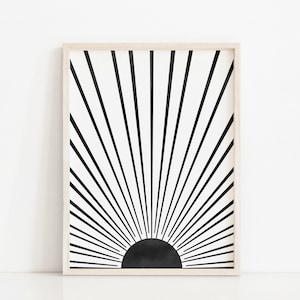 Op de afbeelding: Zwart-witte abstracte kunstprint met een zonnestralenontwerp. De print is ingelijst in een licht houten lijst.