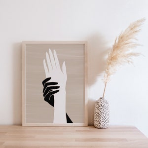 Puede incluir: Una impresi&oacute;n enmarcada de una ilustraci&oacute;n de manos en blanco y negro. Las manos est&aacute;n entrelazadas, con una mano encima de la otra. El fondo es de color beige claro.