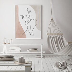 Może przedstawiać: Biały wydruk w ramie z rysunkiem liniowym dw&oacute;ch os&oacute;b, kt&oacute;re się całują. Tło to delikatny r&oacute;żowy i beżowy akwarelowy wash.