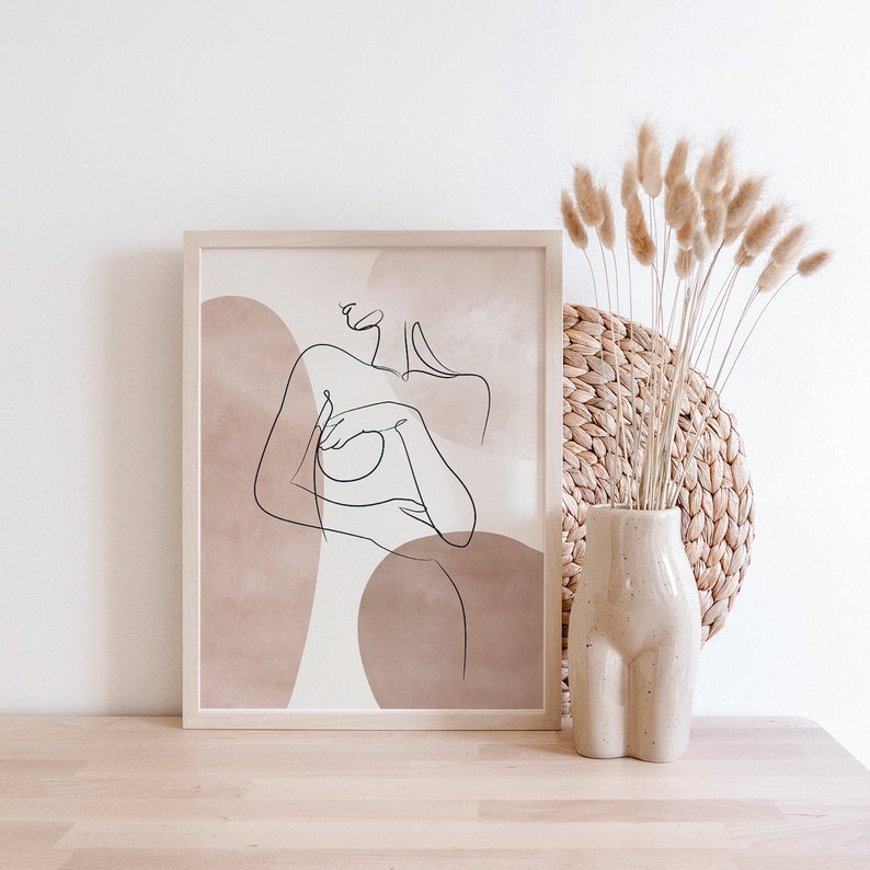 Puede incluir: Una impresi&oacute;n enmarcada con un dibujo lineal de una figura desnuda con formas abstractas en tonos marrones y beige.