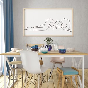 Puede incluir: Una mesa de comedor blanca con cuatro sillas, un taburete y un dibujo en blanco y negro enmarcado de una persona tumbada. La mesa est&aacute; puesta con cuencos azules y blancos, un jarr&oacute;n con flores y una botella de vidrio transparente.