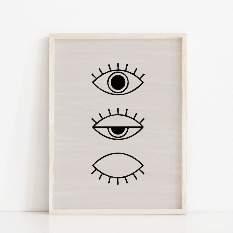 Puede incluir: Una impresi&oacute;n en blanco y negro de tres ojos estilizados con diferentes expresiones. Los ojos est&aacute;n dispuestos verticalmente sobre un fondo beige claro. La impresi&oacute;n est&aacute; enmarcada en un marco de madera claro.