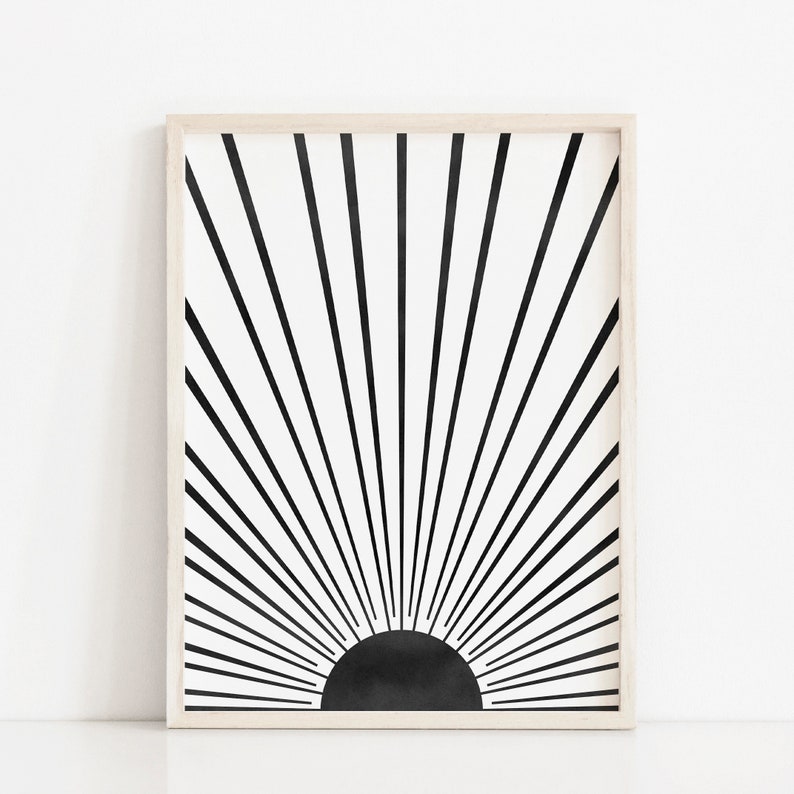 Op de afbeelding: Zwart-witte abstracte kunstprint met een zonnestralenontwerp. De print is ingelijst in een licht houten lijst.