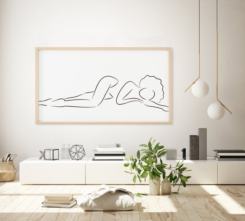Puede incluir: Un dibujo en blanco y negro de una persona acostada, impreso sobre un fondo blanco y enmarcado en un marco de madera claro.
