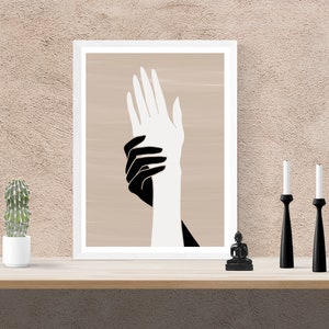 Puede incluir: Una impresi&oacute;n enmarcada de dos manos, una negra y otra blanca, superpuestas sobre un fondo beige.