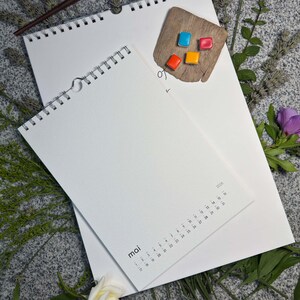Größenvergleich: Maiseite „mai“ im Design Minimal auf dem großen A3-Blankokalender – handgemachte Aquarellnäpfchen und Frühlingsblumen daneben