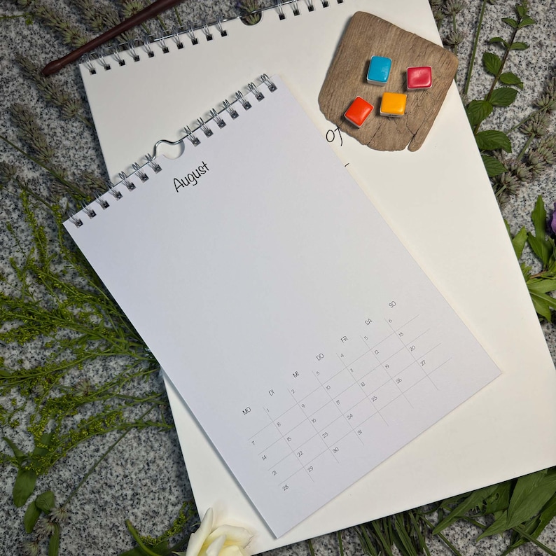 Größenvergleich: Augustseite im Design Classic soft auf dem großen A3-Wandkalender 29,7 × 42 cm – mit bunten Aquarellnäpfchen auf Treibholz