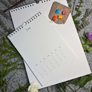 Größenvergleich: kleinerer Kalender mit Juniseite (Design Classic soft) liegt auf dem großen A3-Wandkalender 29,7 × 42 cm – mit Aquarellnäpfchen und Blumen